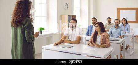 Experienced female teacher who specializes in adult education teaches a lesson to adult students. Stock Photo
