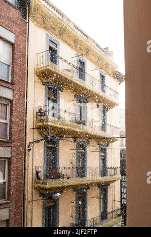 Rain storm water drops falling on the street on a urban scene with a yellow building facade with balconys Stock Photo