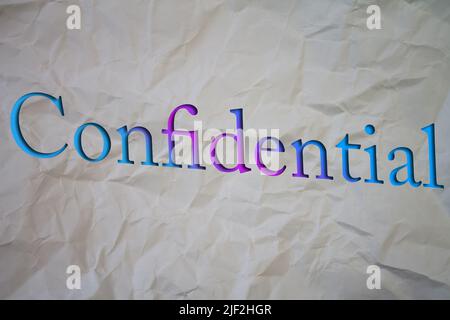 Confidential text with Torn, Crumpled White Paper on colored background. Stock Photo