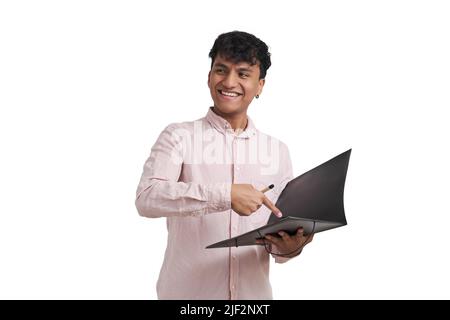 Young peruvian man smiling and pointing at a document in a folder, isolated. Stock Photo