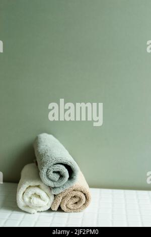 Bathroom towel on white table. khaki green wall background. skin care and spa concept Stock Photo