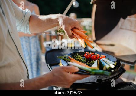 Unrecognizable man preparing vegetables for grilling during family summer garden party, close-up Stock Photo