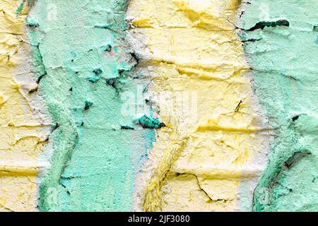 The surface texture of an old used tire with cracks from a truck car is painted with strips of pastel soft green and yellow. Close-up bright summer co Stock Photo