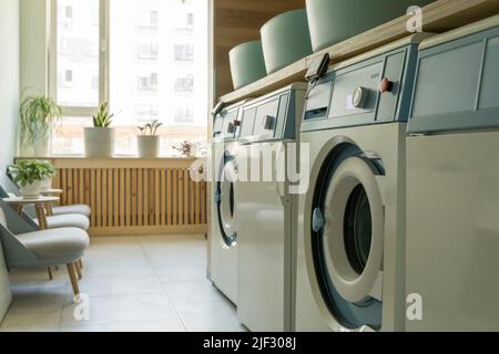 Laundry room interior. Washing machines and dryers in a bright home sunny laundry room. High quality photo Stock Photo