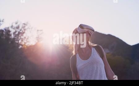 Woman hiking in a forest using a virtual reality headset to enhance the scenic nature. Woman using a virtual reality headset to escape to the Stock Photo