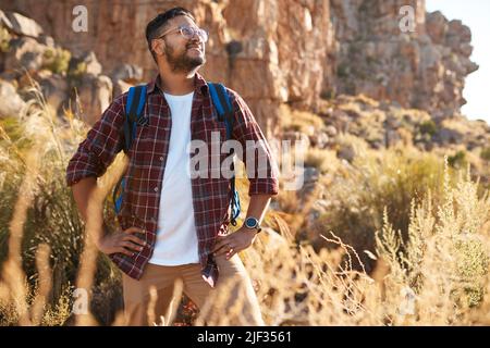 A young adult man stares into the distance while hiking in the rocky mountains Stock Photo