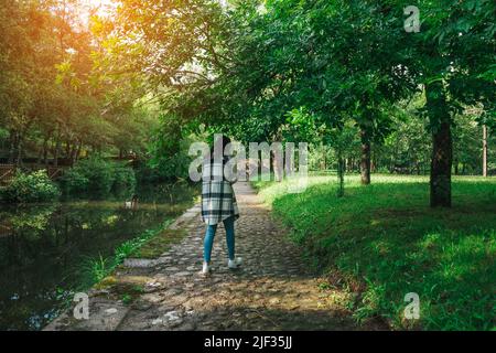 Young woman walking by a path along the river near a forest Stock Photo