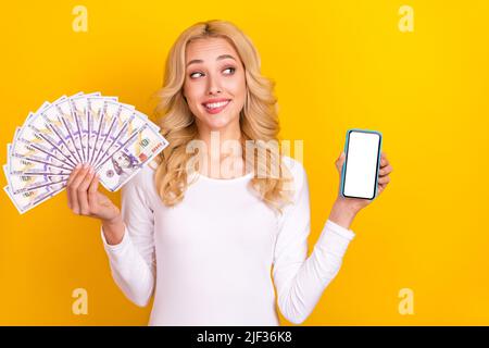 Photo of dreamy sweet woman wear white shirt rising money fan gadget empty space isolated yellow color background Stock Photo