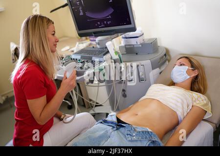 Doctor examines woman with ultrasound scanner closeup Stock Photo