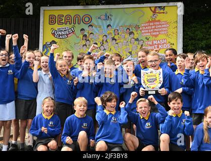 EDITORIAL USE ONLY Pupils from Voyager Year 5 class at Whitehill Junior School unveil a billboard illustrating their winning joke as they are presented with the Beano 'Britain's Funniest Class' trophy by the comic staff writer Danny Pearson, Hertfordshire. Picture date: Wednesday June 29, 2022. The class came up with the winning joke, 'What do you call a class of children who eat potatoes using their toes? - The Mash Street Kids!'. The competition was fierce this year with hilarious jokes coming in from across the nation and receiving over 190,000 votes by the public. The annual initiative, cr Stock Photo