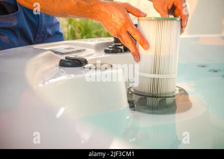 Hot Tub Technician Performing Scheduled Garden SPA Maintenance. Checking Residue on the Water Filter. Residential Garden Hot Tub Service. Water Qualit Stock Photo