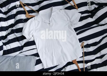 White cotton golf shirt mockup over the striped background. Classic look blank golf shirt. Stock Photo