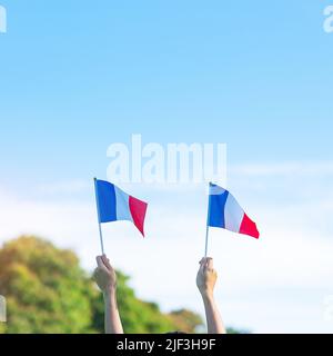 hand holding France flag on blue sky background. holiday of French National Day, Bastille Day and happy celebration concepts Stock Photo