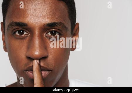 Young black man showing silence gesture at camera isolated over white wall Stock Photo