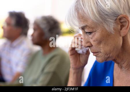 Close-up of asian senior woman crying while sitting with multiracial friends in nursing home Stock Photo