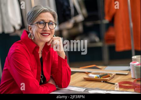 Successful woman smiling at camera sitting in atelier Stock Photo