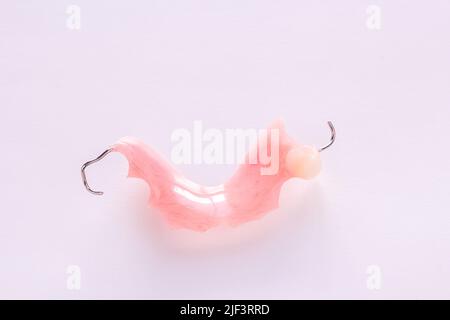 Close up acrylic denture with metal clasps for restoring dentition on white background. Health and medical concept. Stock Photo