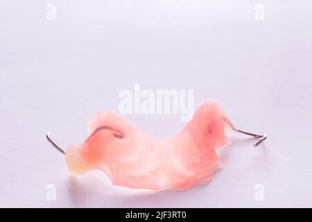 Close up acrylic denture with metal clasps for restoring dentition on white background. Health and medical concept. Stock Photo