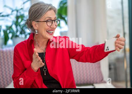 Emotional woman looking at smartphone in outstretched hand Stock Photo