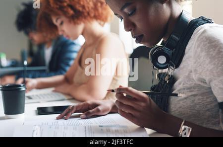 A diverse group of students reading paperwork and studying. A young student reading her academic texts before making notes. A serious academic student Stock Photo