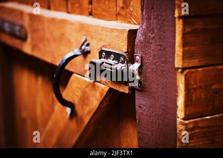 An old wooden gate with an open metal latch and handle. Village life. Stock Photo