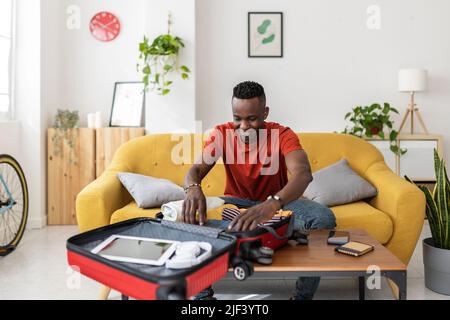 Young man packing travel bag for summer vacation Stock Photo