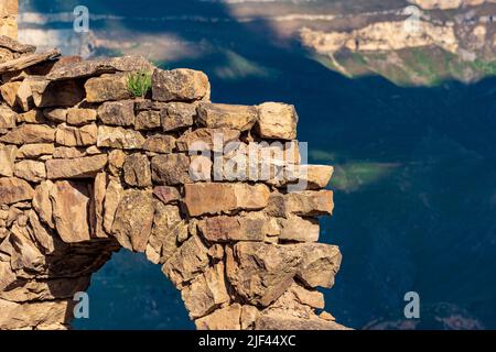 detail of an old dilapidated stone arch against the background of a blurred mountain slope with shadows from the clouds Stock Photo