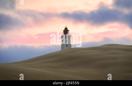 The view of Rubjerg Knude Lighthouse behind the dunes against cloudy sky at sunset. Denmark. Stock Photo