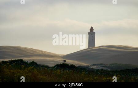 The view of Rubjerg Knude Lighthouse behind the dunes at sunset. Denmark. Stock Photo