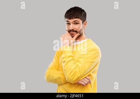 thinking young man in yellow sweatshirt Stock Photo