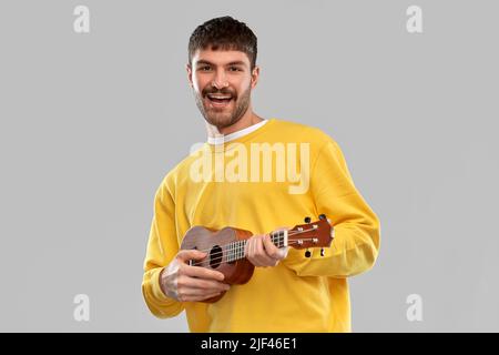 smiling young man playing ukulele guitar Stock Photo