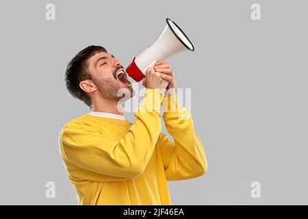 man in yellow sweatshirt shouting to megaphone Stock Photo