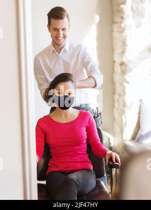 happy woman with stylist making hairdo at salon Stock Photo
