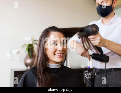 happy woman with stylist making hairdo at salon Stock Photo