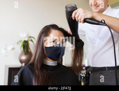 happy woman with stylist making hairdo at salon Stock Photo