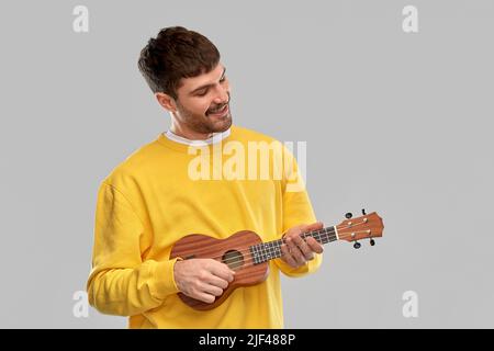 smiling young man playing ukulele guitar Stock Photo