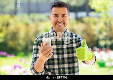 man with smartphone showing thumbs up at garden Stock Photo