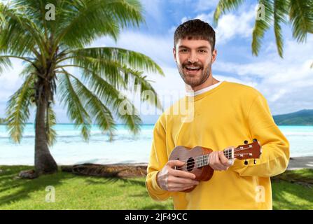 smiling young man playing ukulele guitar Stock Photo