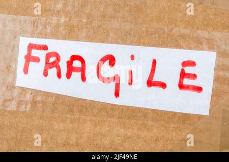 Brown cardboard shipping box with handwritten red on white 'Fragile' label. For something fragile and delicate. Stock Photo