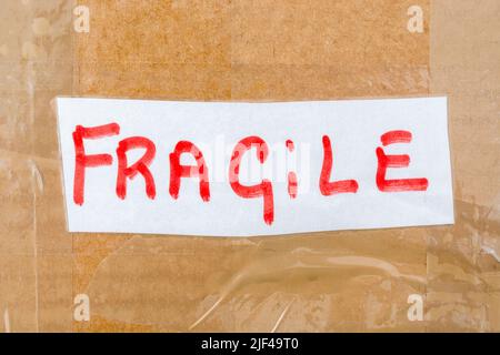 Brown cardboard shipping box with handwritten red on white 'Fragile' label. For something fragile and delicate. Stock Photo