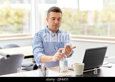 man using hand sanitizer at home office Stock Photo