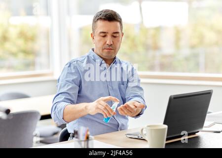 man using hand sanitizer at home office Stock Photo
