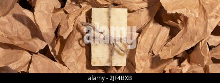 Natural handmade organic soap on multiple pieces of torn brown craft paper background, top view banner. Zero waste, eco friendly vegan soap bar. Wide Stock Photo
