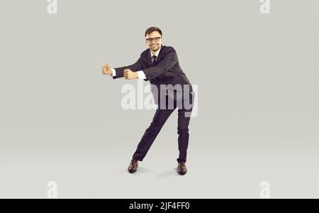 Young Caucasian business man smiles and performs victory dance, stands on studio background Stock Photo
