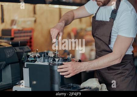 Close up of man hands repairing coffee machine in a workshop Stock Photo