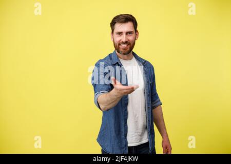 Handsome man over yellow background inviting to come with hand. Happy that you came Stock Photo