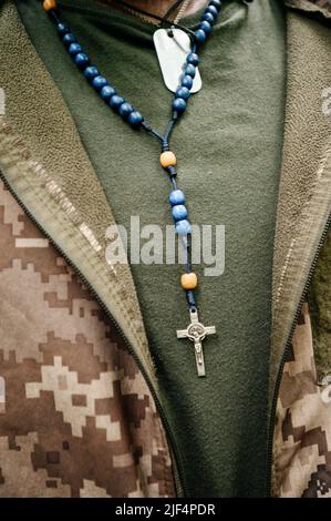 The Ukrainian military wears a rosary and military dog tags on his chest, faith in God. Stock Photo