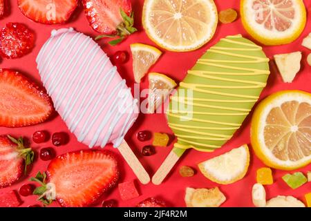 Two ice creams on a sticks - strawberry and lemon on a red background. Summer fruit desserts Stock Photo