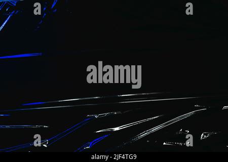 Transparent plastic wrap on black background. Crumpled wrinkled plastic cellophane. Reflecting blue color light and shadow on creases and folds in Stock Photo