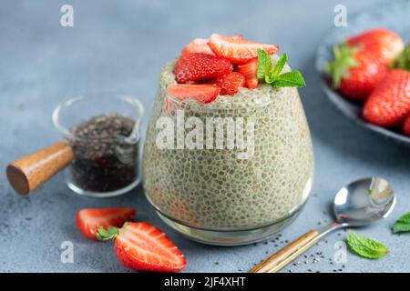 Chia pudding with strawberries in glass jar on blue stone background, closeup view Stock Photo
